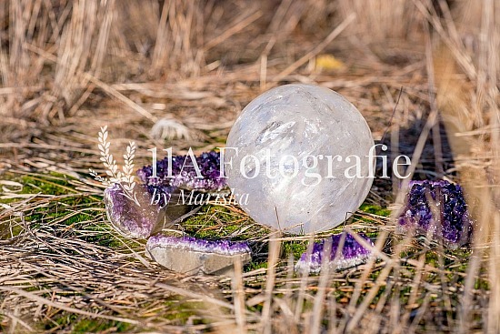 Bergkristal bal omringt door ruwe Amethist edelstenen